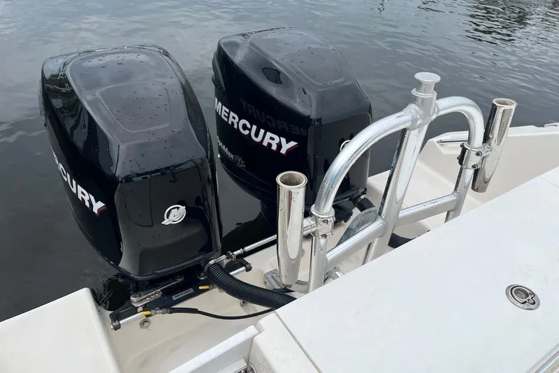 Slide: The Image of Twin Mercury outboard engines on a 2011 Angler 2600 CC boat, docked on calm water. - 8