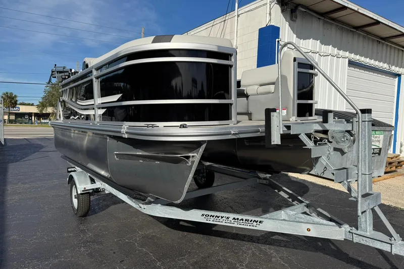 Slide: The Image of 2025 SunCatcher Select 16C pontoon boat on trailer, parked outside a building. - 1