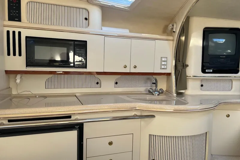Slide: The Image of 2001 Sea Ray 310 Sundancer interior kitchen with microwave, sink, and TV. - 7