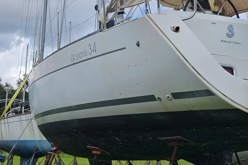 Slide: The Image of 2010 Beneteau Oceanis 34 GT sailboat on stands in a grassy boatyard. - 2