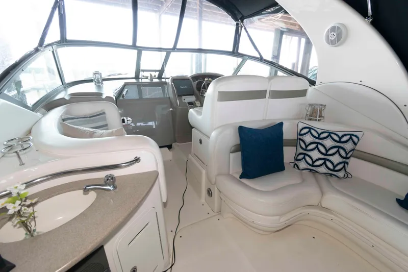 Slide: The Image of 2006 Sea Ray 320 Sundancer interior with TV, plush seating, and decorative pillows. - 2