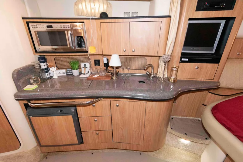 Slide: The Image of 2006 Sea Ray 320 Sundancer kitchen with microwave, sink, and wooden cabinetry. - 22