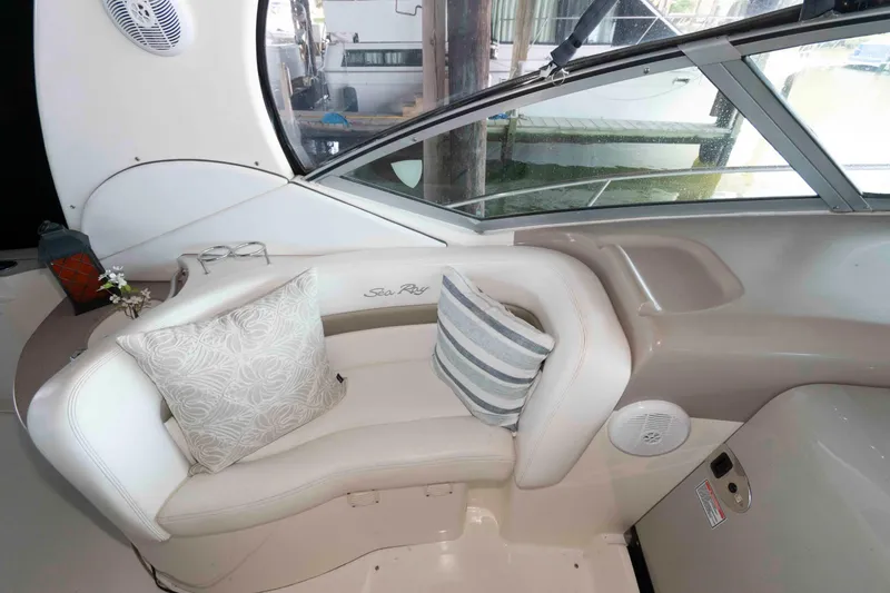 Slide: The Image of 2006 Sea Ray 320 Sundancer interior with stylish cushions, docked under a wooden canopy. - 8