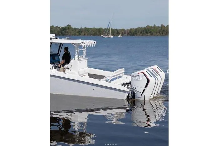 Slide: The Image of 2024 Fountain Bluewater 38 Tournament Edition boat on calm lake with triple outboard engines. - 10