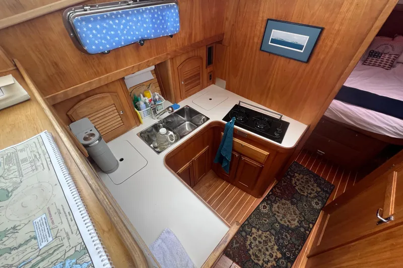 Slide: The Image of 2004 Sabre 36 Hardtop Sedan interior with compact kitchen and wooden cabinetry. - 10
