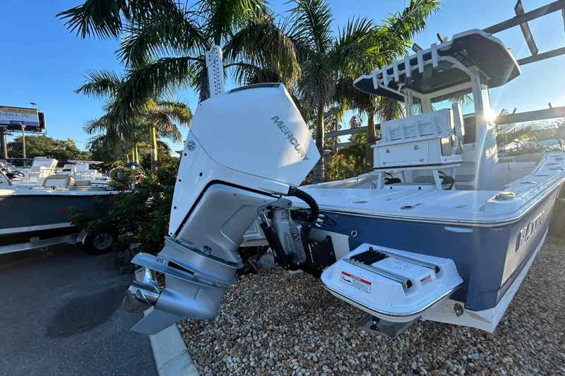 Slide: The Image of 2026 Blackfin 242 HB boat with Mercury outboard engine, parked near palm trees. - 2