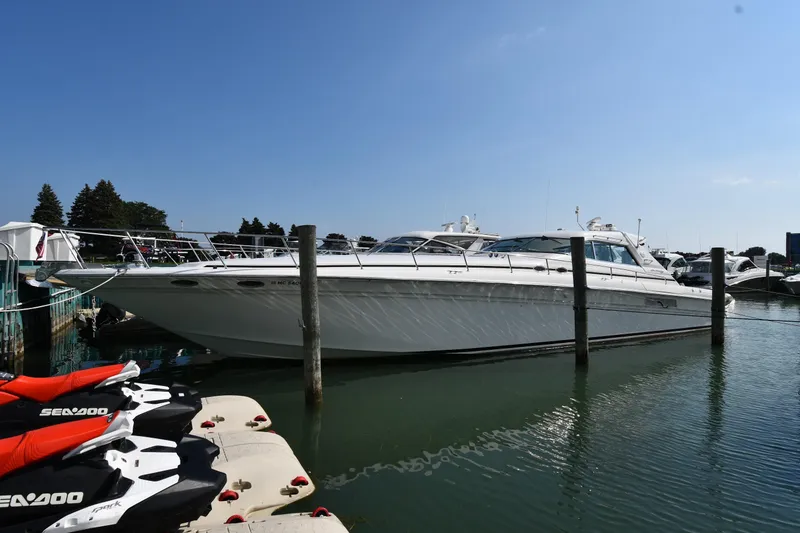 The Image of 1995 Sea Ray 630 Sundancer yacht docked beside jet skis in a marina. - 1