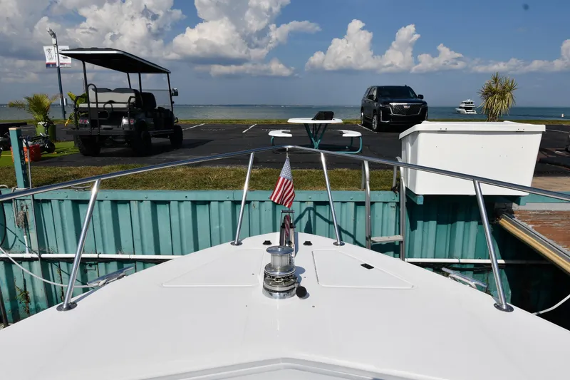 Slide: The Image of 1995 Sea Ray 630 Sundancer docked, with vehicles and ocean view in the background. - 4