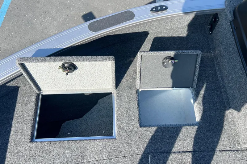 Slide: The Image of 2026 Crestliner 2050 Fish Hawk boat storage compartments with open hatches on carpeted deck. - 11
