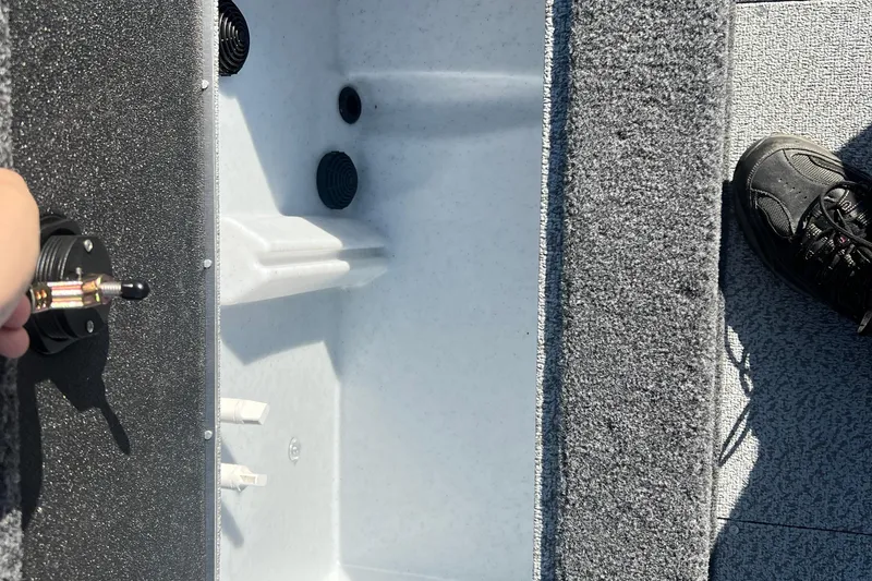 Slide: The Image of Interior view of 2026 Crestliner 2050 Fish Hawk boat, showing storage compartment and carpeted flooring. - 32