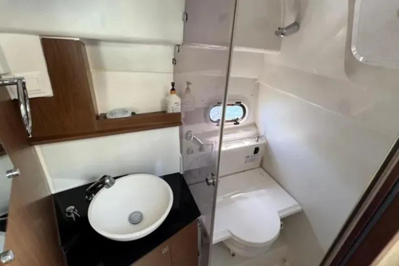 Slide: The Image of 2020 Jeanneau Leader 9.0 WA boat bathroom with sink, toilet, and porthole window. - 16