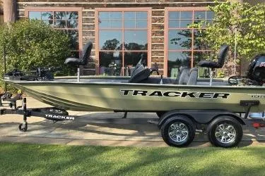 The Image of 2026 Tracker Pro Team 195 boat on trailer, parked outdoors near a building. - 0