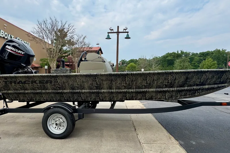 The Image of 2026 Tracker Grizzly 1648 SC boat on trailer, parked outside a boat center. - 0