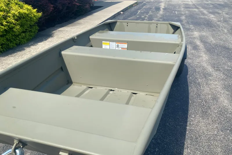 Slide: The Image of 2026 Tracker Grizzly 10 Jon boat on pavement, showcasing interior seating and storage. - 3