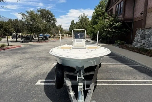 Slide: The Image of 2026 Mako 18 Pro Skiff boat on trailer in parking lot, surrounded by trees. - 2