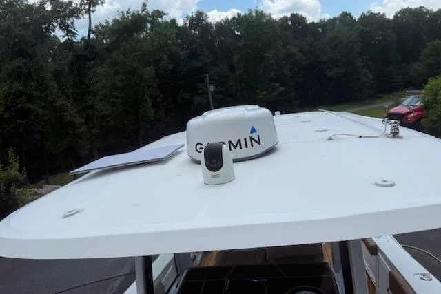 Slide: The Image of 2022 Sea Hunt Gamefish 30 boat roof with Garmin equipment, surrounded by trees. - 12