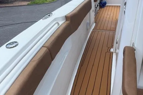 Slide: The Image of 2022 Sea Hunt Gamefish 30 Forward Seating with teak-style deck and cushioned side rails. - 13