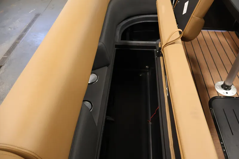Slide: The Image of 2026 Bentley Pontoons Elite 253 storage compartment with tan and black interior design. - 13