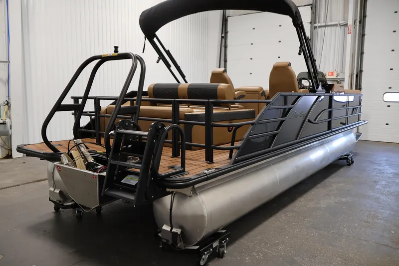 Slide: The Image of 2026 Bentley Pontoons Elite 253 Swingback Tri-Toon with dual captain chairs in a showroom. - 4