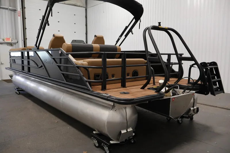 Slide: The Image of 2026 Bentley Pontoons Elite 253 Swingback Tri-Toon with dual captain chairs in a showroom. - 6
