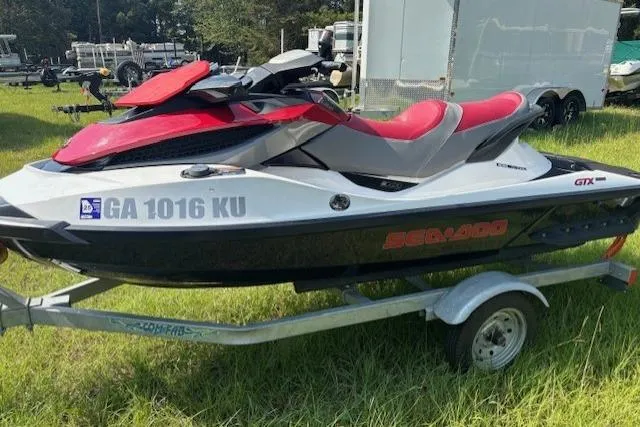 Slide: The Image of 2010 Sea-Doo GTX 155 jet ski on trailer, red and black, parked on grass. - 7