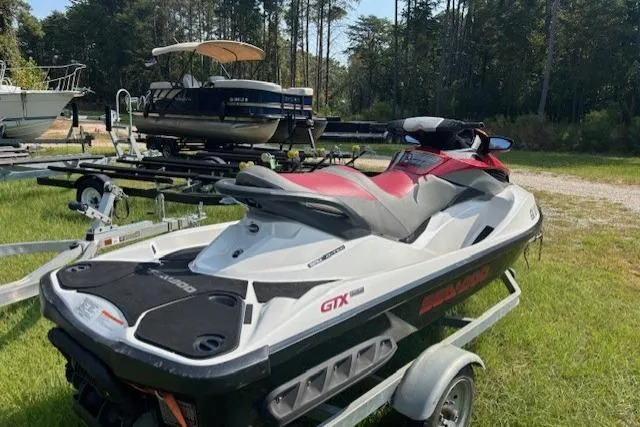 Slide: The Image of 2010 Sea-Doo GTX 155 jet ski on trailer, parked outdoors near other boats. - 9