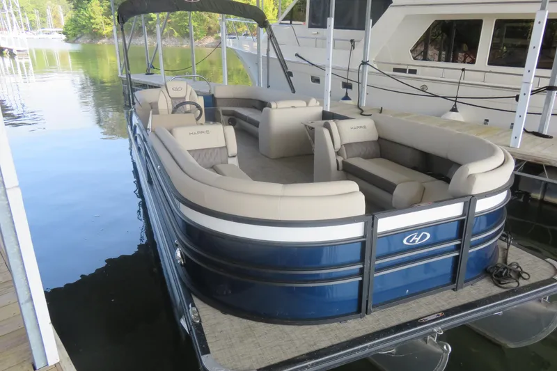 Slide: The Image of 2023 Harris Sunliner 250 pontoon boat docked, featuring spacious seating and elegant design. - 13