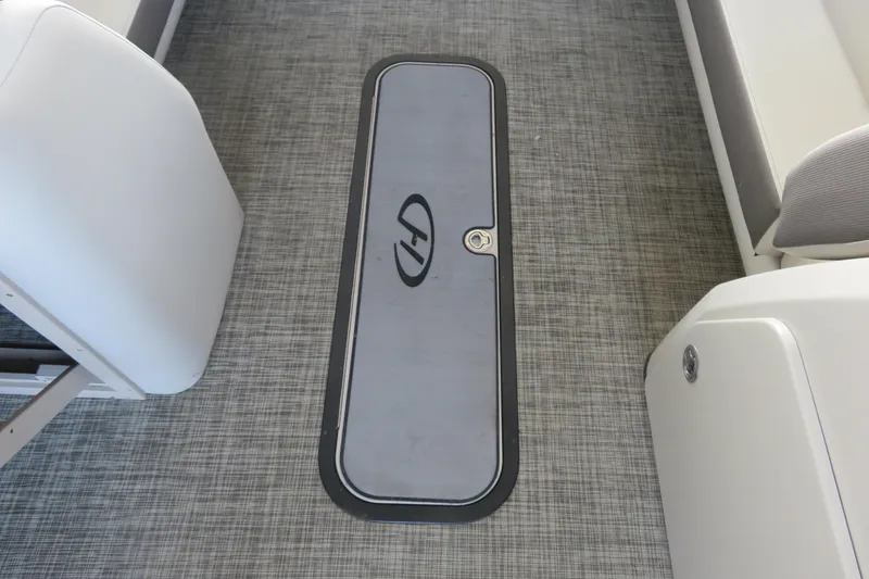 Slide: The Image of 2023 Harris Sunliner 250 boat interior with gray flooring and storage compartment. - 4
