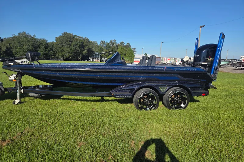 Slide: The Image of 2018 Skeeter FX20 bass boat on trailer, parked on grass under clear sky. - 2