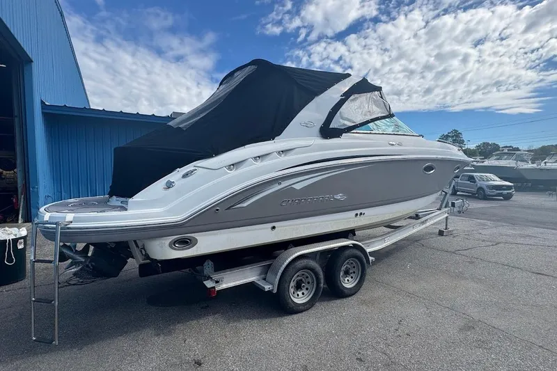 Slide: The Image of 2010 Chaparral 275 SSi boat on trailer, parked near blue building under cloudy sky. - 3