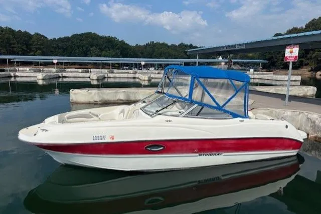 The Image of 2005 Stingray 220 DR boat docked at marina with blue canopy and red stripe. - 1