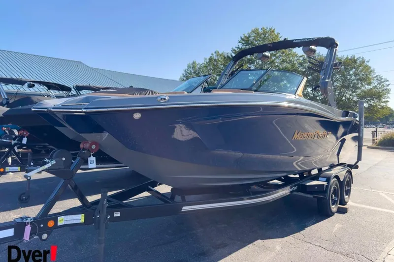 Slide: The Image of 2026 MasterCraft XT22 boat on trailer, displayed outdoors in a dealership lot. - 7