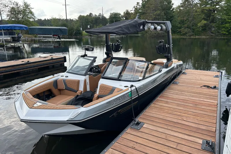 Slide: The Image of 2022 Nautique Super Air Nautique G21 boat docked on a serene lake. - 1