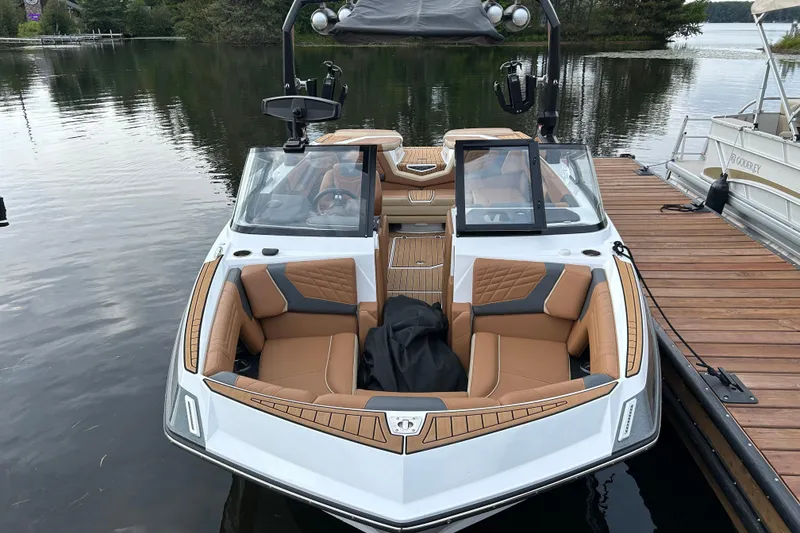 Slide: The Image of 2022 Nautique Super Air Nautique G21 boat docked on a calm lake. - 2