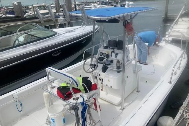 Slide: The Image of 1999 Edgewater 220CC boat docked, featuring a blue canopy and equipped console. - 6