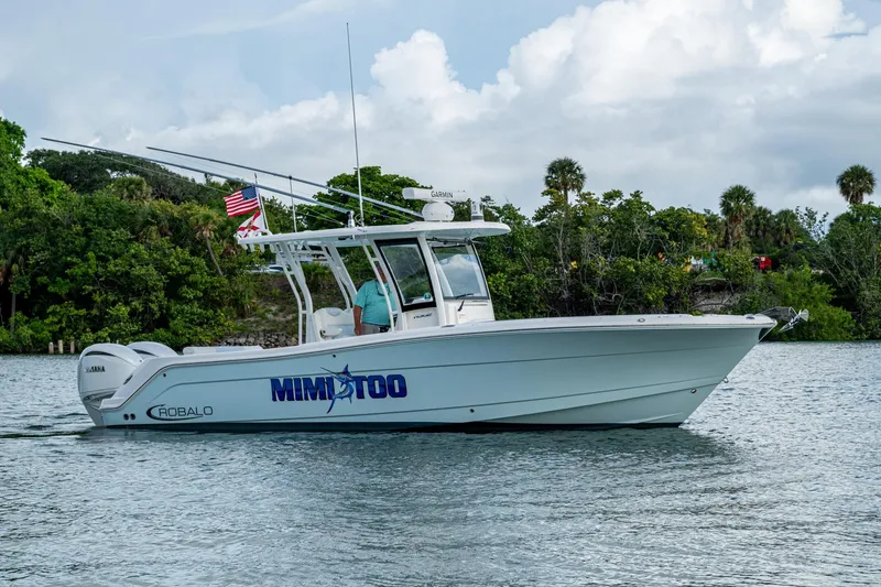 Slide: The Image of 2023 Robalo R302 Center Console boat on water, lush greenery background. - 18
