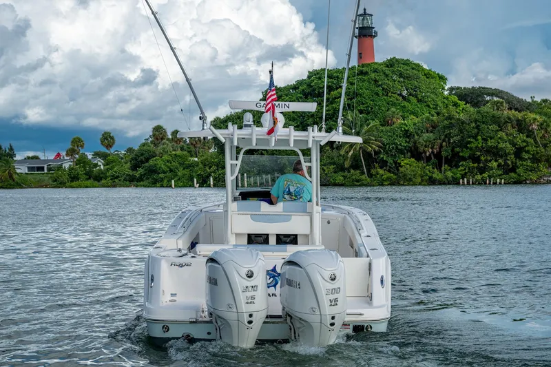 Slide: The Image of 2023 Robalo R302 Center Console boat cruising near lush greenery and lighthouse. - 2