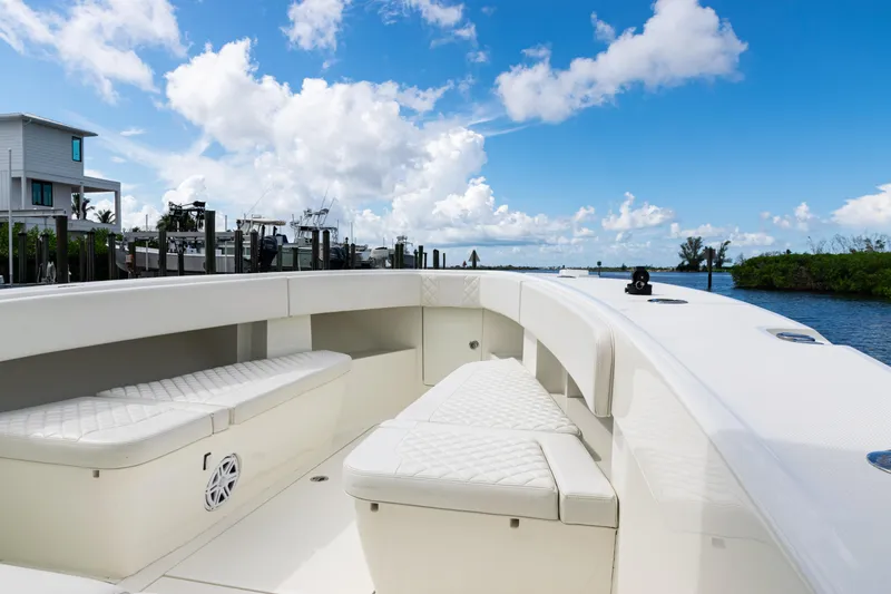 Slide: The Image of 2017 SeaVee 370z boat interior with white seating, docked by a waterfront home. - 14
