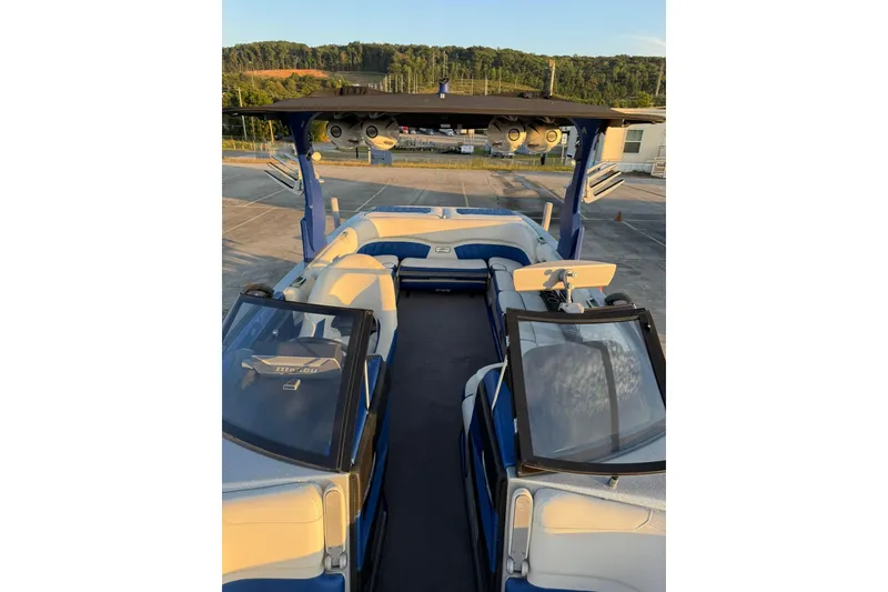 Slide: The Image of 2016 Malibu Wakesetter 25 LSV boat interior with blue and white seating, parked outdoors. - 14