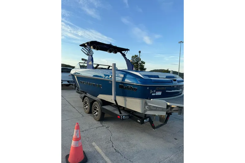 Slide: The Image of 2016 Malibu Wakesetter 25 LSV boat on trailer, blue exterior, parked outdoors. - 2