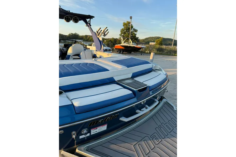 Slide: The Image of 2016 Malibu Wakesetter 25 LSV boat with blue and white seating, docked outdoors. - 3