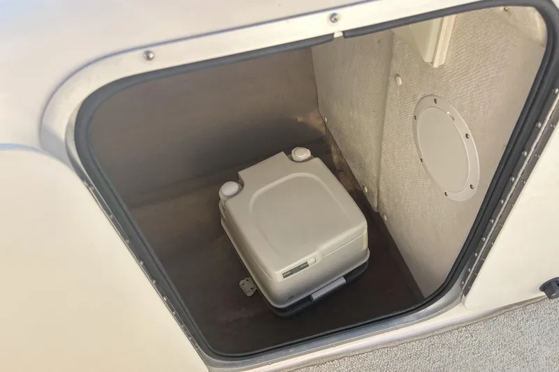Slide: The Image of 1998 Chaparral Sunesta 210 boat storage compartment with portable toilet. - 13