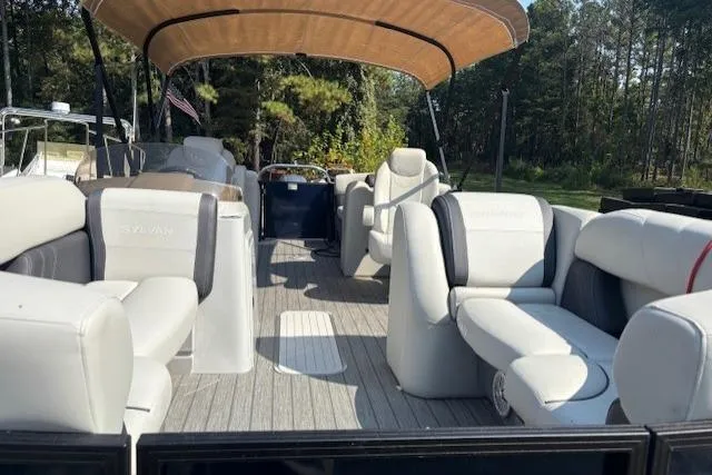 Slide: The Image of 2023 Sylvan Mirage X X3 pontoon boat with spacious seating and canopy, set in a wooded area. - 4