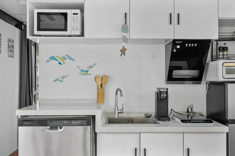 Slide: The Image of Modern kitchen with white cabinets, appliances, and decorative wall art. Gospel 39, 2024 model. - 10