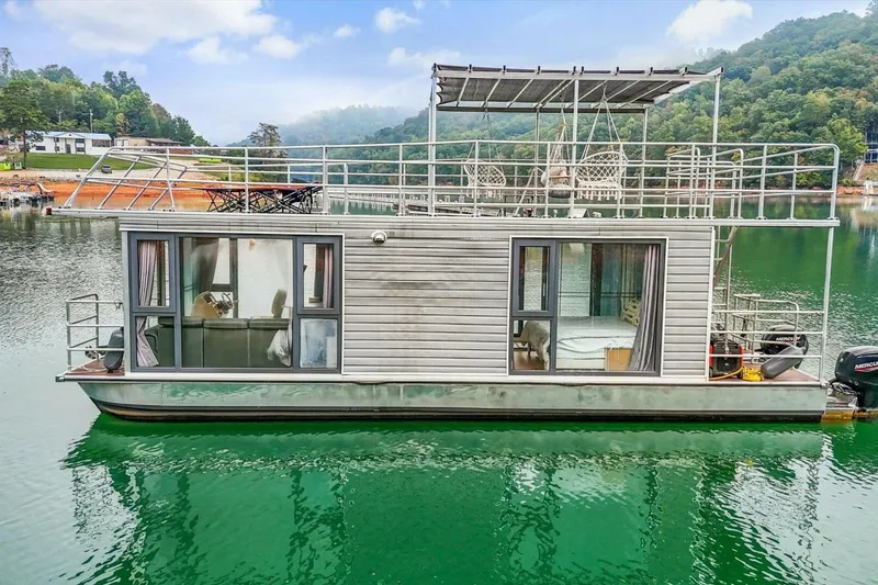 Slide: The Image of Modern 2024 Gospel 39 houseboat on serene lake with lush green surroundings. - 3