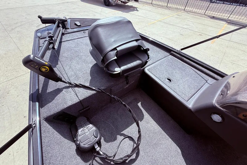 Slide: The Image of 2025 Bass Tracker Classic XL boat interior with seating and canopy, parked outdoors. - 9