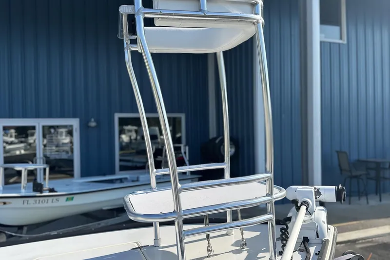 Slide: The Image of 2004 Hells Bay 18 Marquesa boat with metal framework, docked near blue building. - 4