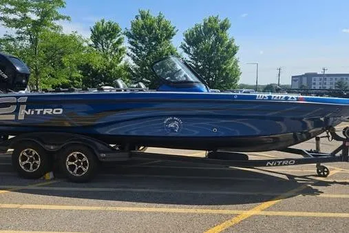 The Image of 2016 Nitro ZV21 Pro boat on trailer, parked outdoors, with trees and buildings in background. - 1