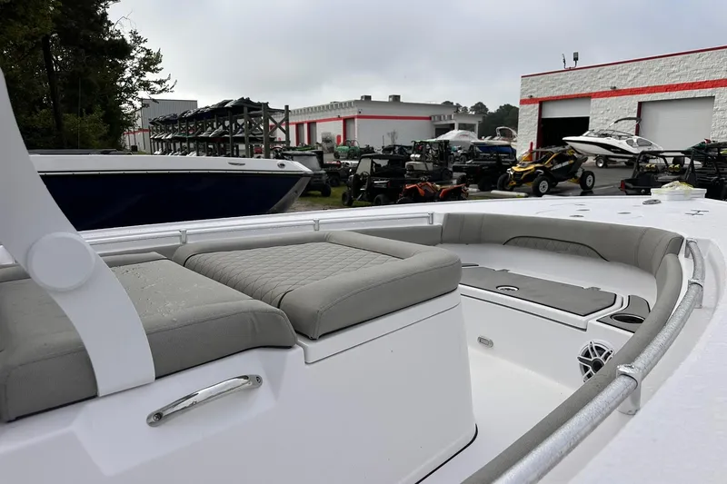 Slide: The Image of 2025 Sportsman Masters 247OE Bay Boat interior with cushioned seating, parked near dealership. - 5