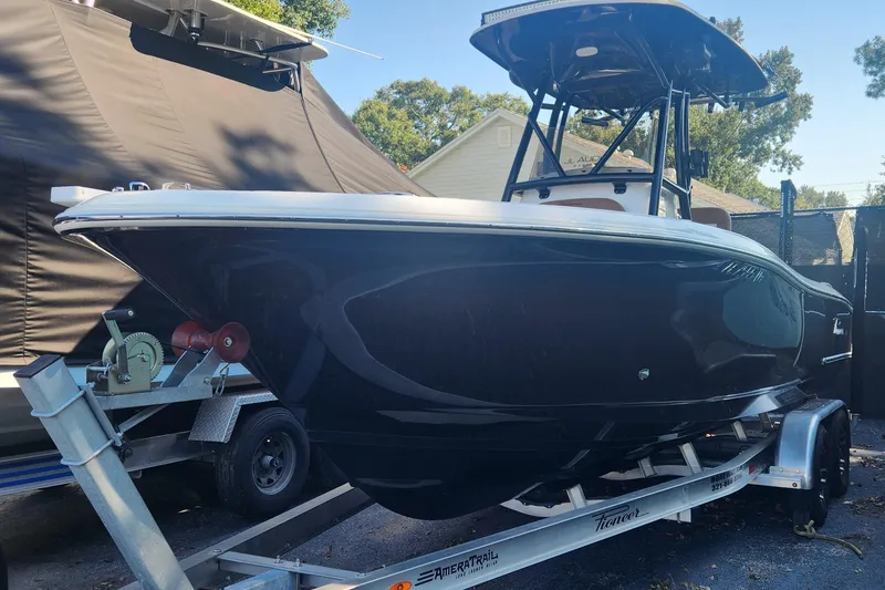 The Image of 2022 Pioneer 222 Islander boat on trailer, black hull, outdoor setting. - 1